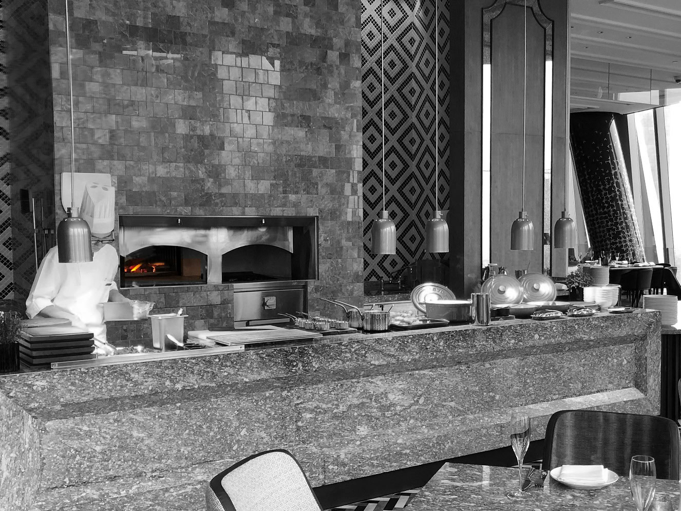 Bespoke stone hearth oven set into a kitchen wall of patterned tiles above a stone counter
