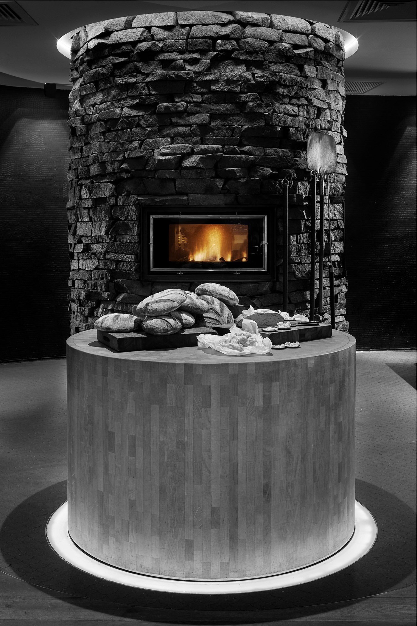 Cylindrical stone hearth oven burning above a display of freshly baked bread loaves